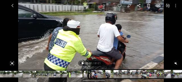 Ditengah Hujan dan Banjir, Kasat Lantas Polres Dumai Dorong Motor dan Seberangkan Pelajar Sekolah